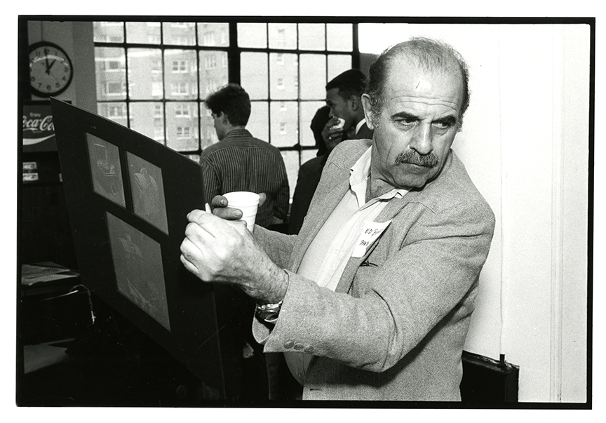 Ed Benguiat holding a poster board and cup